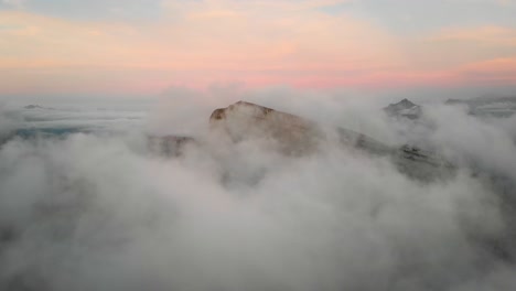 aerial flyover through clouds in leysin, vaud, switzerland during a colorful autumn sunset with hikers on tour d'aï enjoying the panoramic view above clouds with tour de mayen in the background