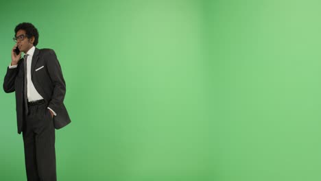 businessman walking and talking on phone with green screen
