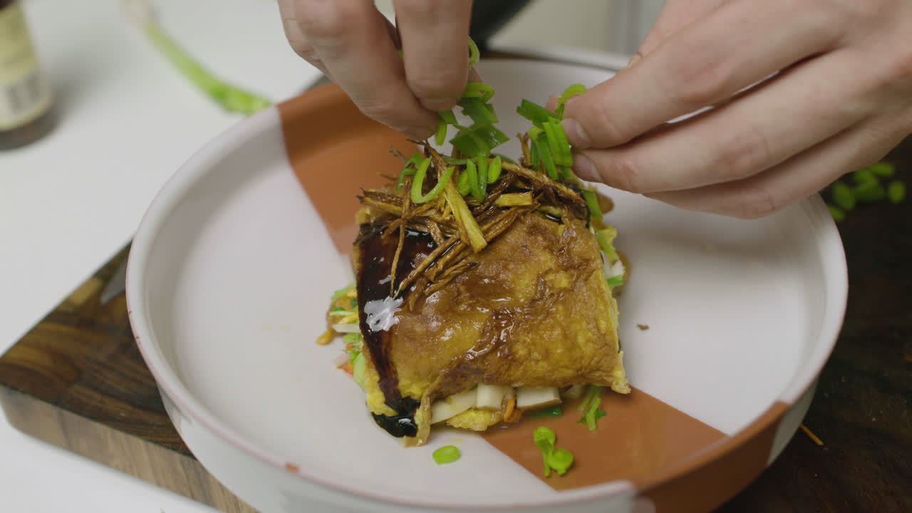 Decorating egg and abalone seafood dish with greens on top