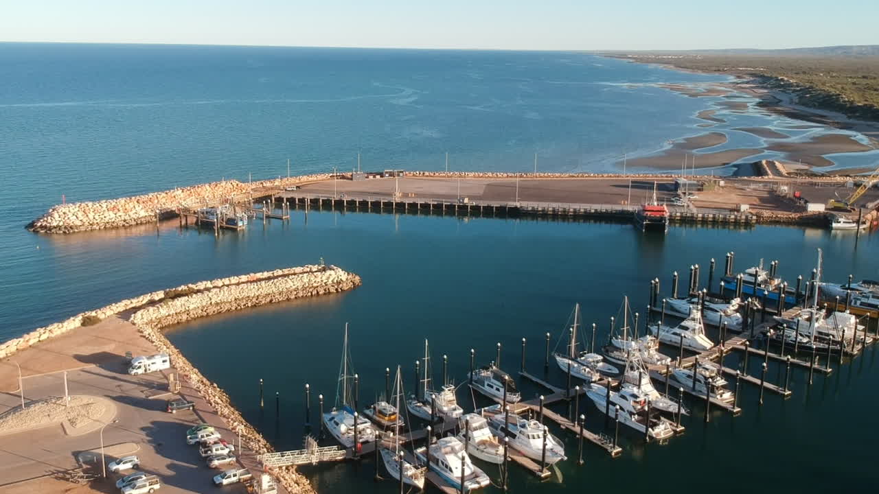 puerto de video de drones cinematográficos con muchos barcos grandes durante la puesta de sol con luz solar cálida en un lugar tranquilo