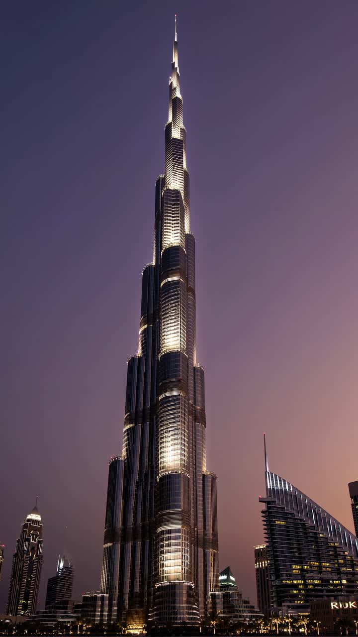 A towering skyscraper captured from a low-angle at dusk, highlighting its illuminated facade