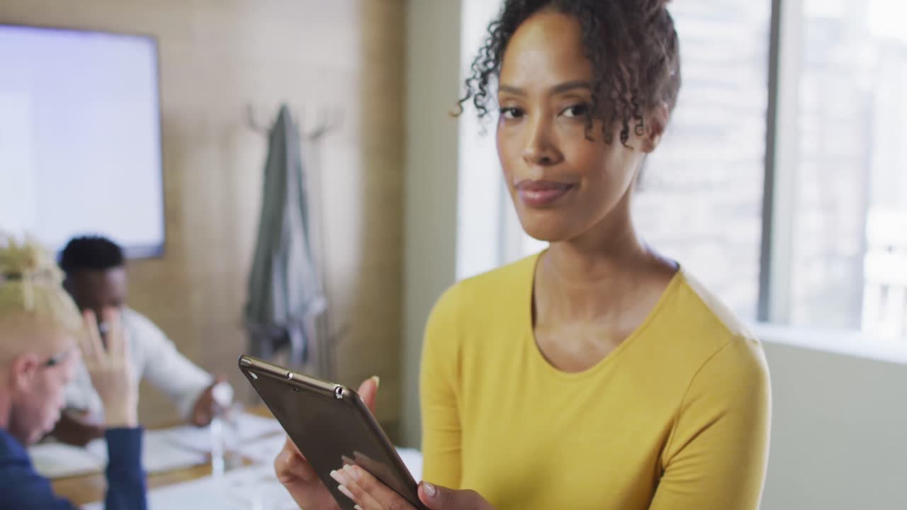 Portrait of happy african american businesswoman with tablet in creative office