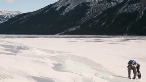 niña excursionista deslizándose por una losa de hielo gigante en hermosas montañas de invierno en el lago congelado minnewanka en el parque nacional de banff alberta canadá en un día soleado al aire libre