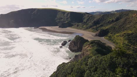 outstanding aerial pull back above forested rock formation on seaside