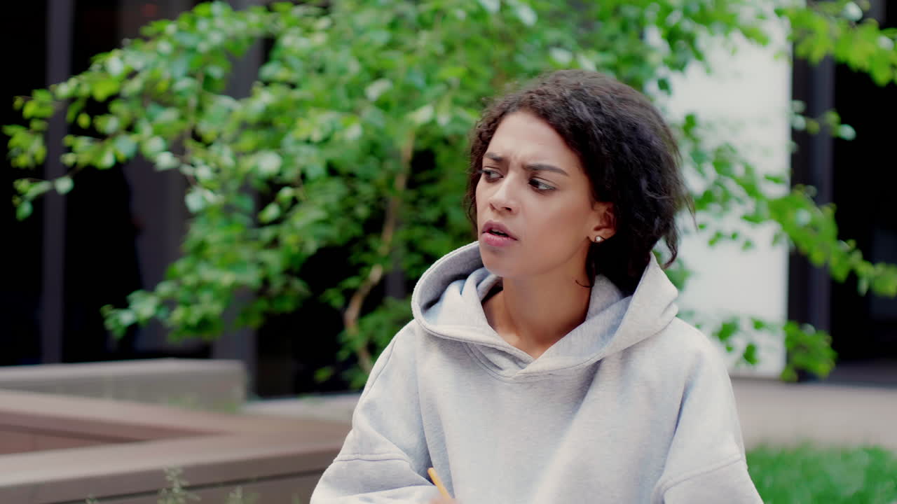 una chica afroamericana pensativa en el campus de la universidad.