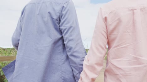 웃는 고위 백인 커플이 손을 잡고 야외의 길을  ⁇ 고 있습니다.