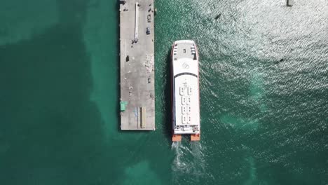 Aerial-drone-tracking-video-of-ferry-Utila-dream-in-deep-blue-open-Caribbean-sea,-arriving-to-embarkation-point-of-the-island-of-Utila,-Honduras