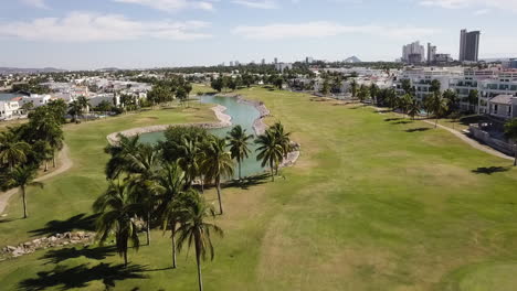 Vista-Aérea-De-Un-Campo-De-Golf-Con-Laguna-Artificial-Y-Palmeras,-México