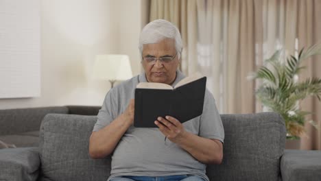 Serious-Indian-old-man-reading-book-in-morning