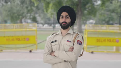 portrait of confident sikh indian police man standing crossed hands