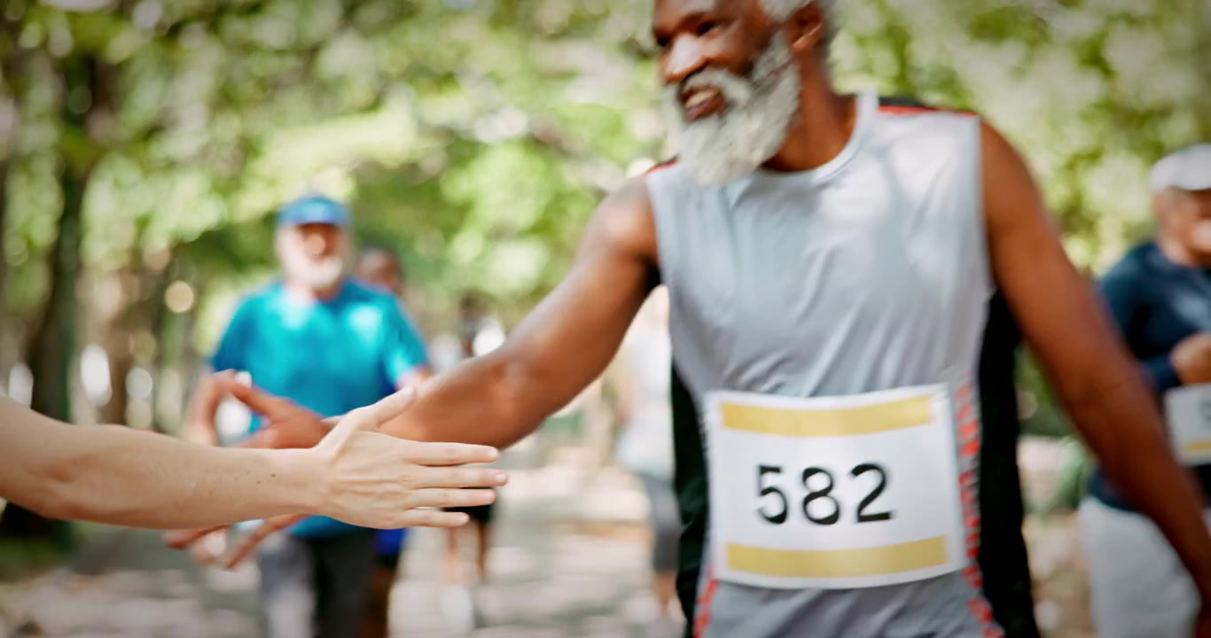 Gruppo eterogeneo di corridori che danno il cinque a uno spettatore durante una maratona