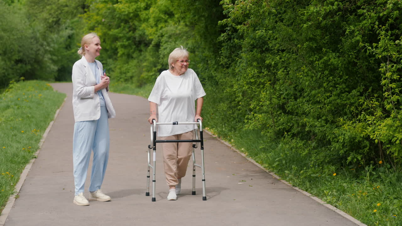 Young woman assisting elderly woman on a walker in a park