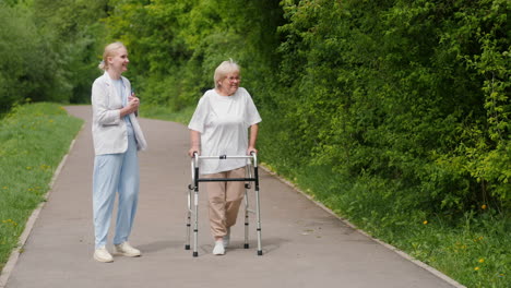 joven ayudando a una anciana en un andador en un parque