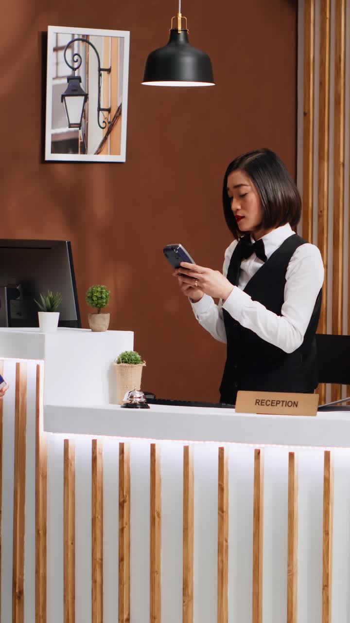 Video verticale: viaggiatore asiatico che paga la camera d'albergo durante il check-in