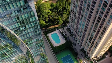 Inclinándose-Lentamente-Hacia-Abajo,-Una-Foto-De-Una-Piscina-Y-Una-Cancha-De-Tenis-Entre-Dos-Rascacielos-En-Buckhead,-Atlanta,-Georgia