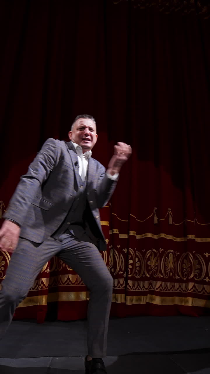 Middle age male entertainer, presenter or actor on stage. Public speaker gives performance. Man in theater. Vertical video