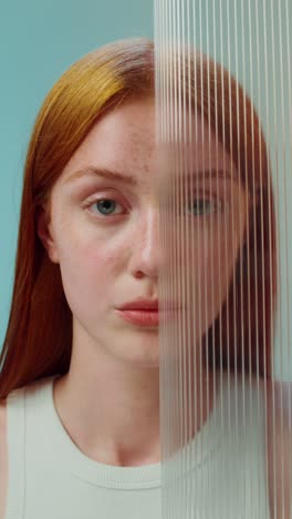 woman with red hair and freckles behind a transparent panel