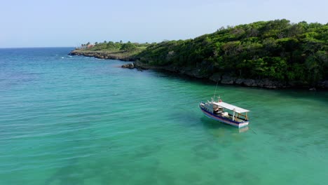 Vuelo-A-Baja-Altura-A-La-Sombra-De-Un-Barco-Anclado-En-La-Playa-Diamante,-Cabrera-República-Dominicana