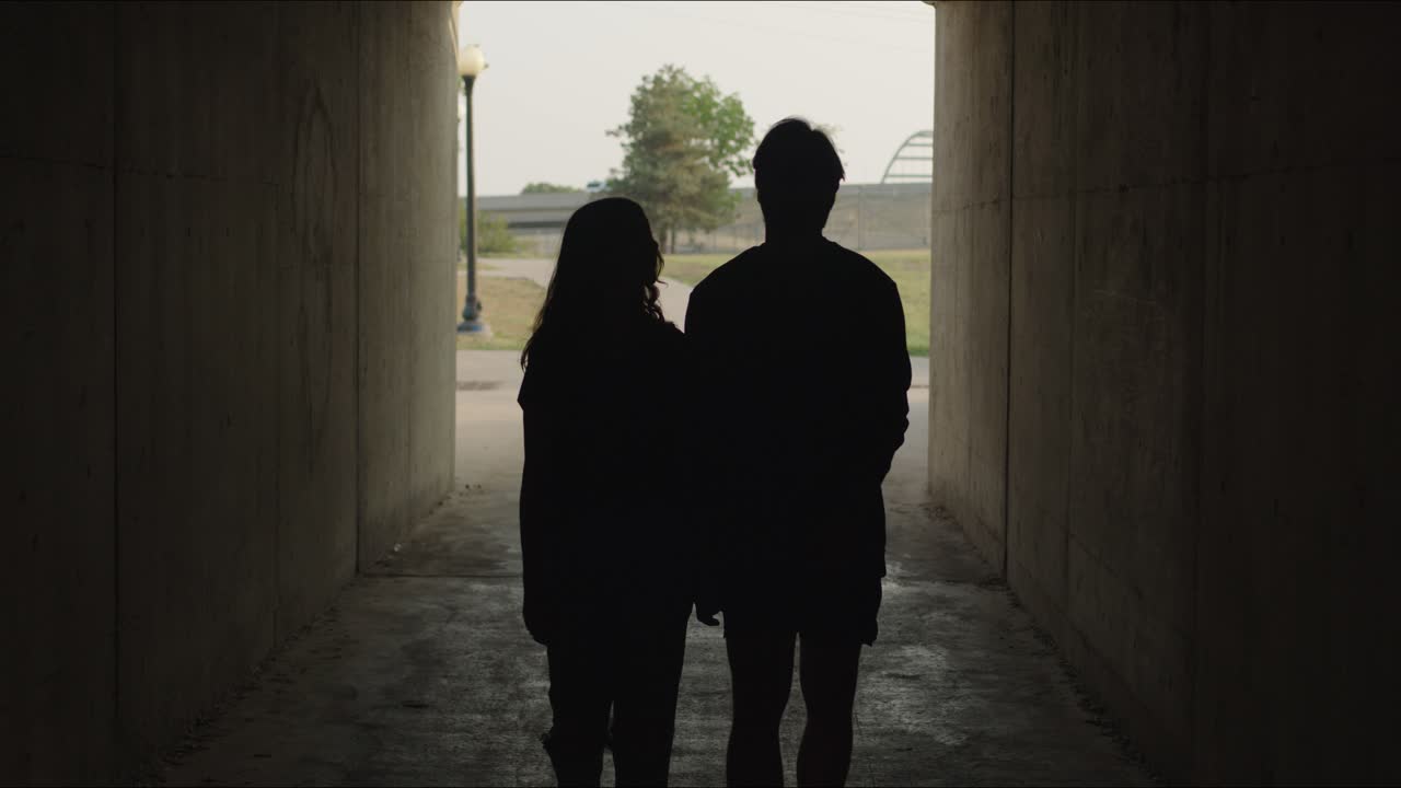 Couple walks in silhouette through alley