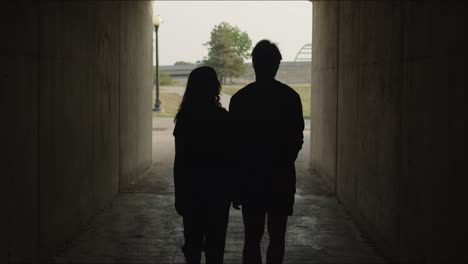couple walks in silhouette through alley