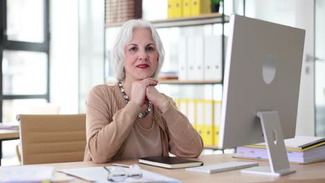 senior woman working at an office desk with a computer