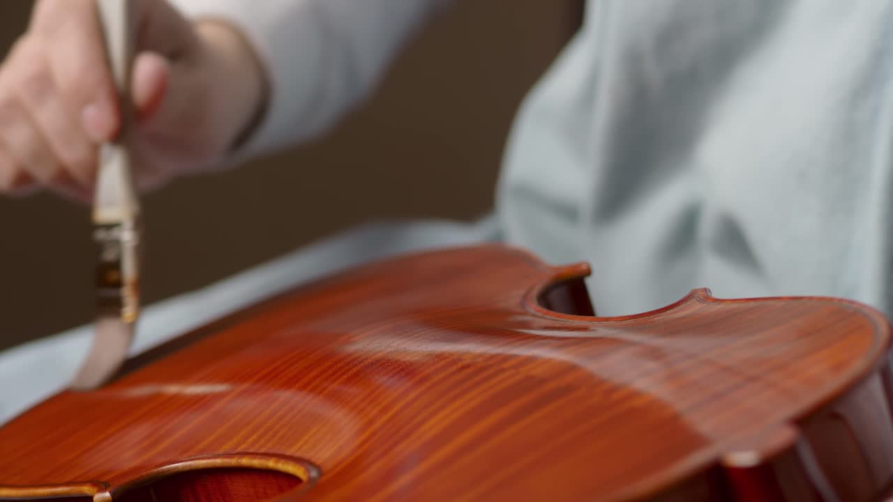 Master violin maker artisan varnishing handmade classical violin with self produced natural paint, with precise brush strokes and focus, slow motion footage