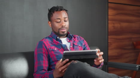 man using a tablet on a couch