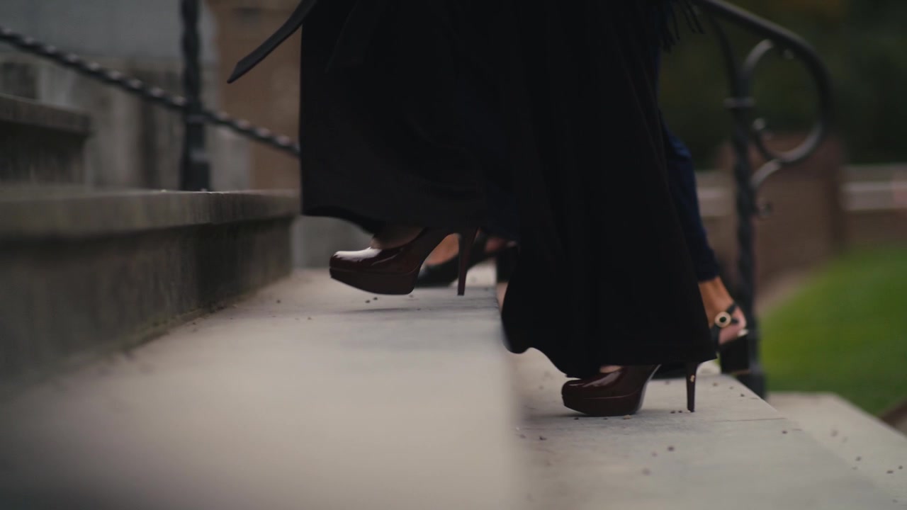 Donna che indossa abiti eleganti e tacchi, mentre sale una scalinata.