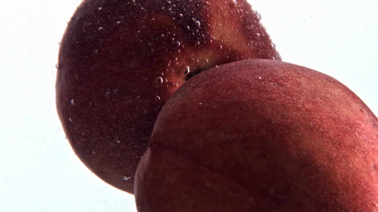 melocotones girando agua gaseosa en cámara lenta. agua fría frutas jugosas girando