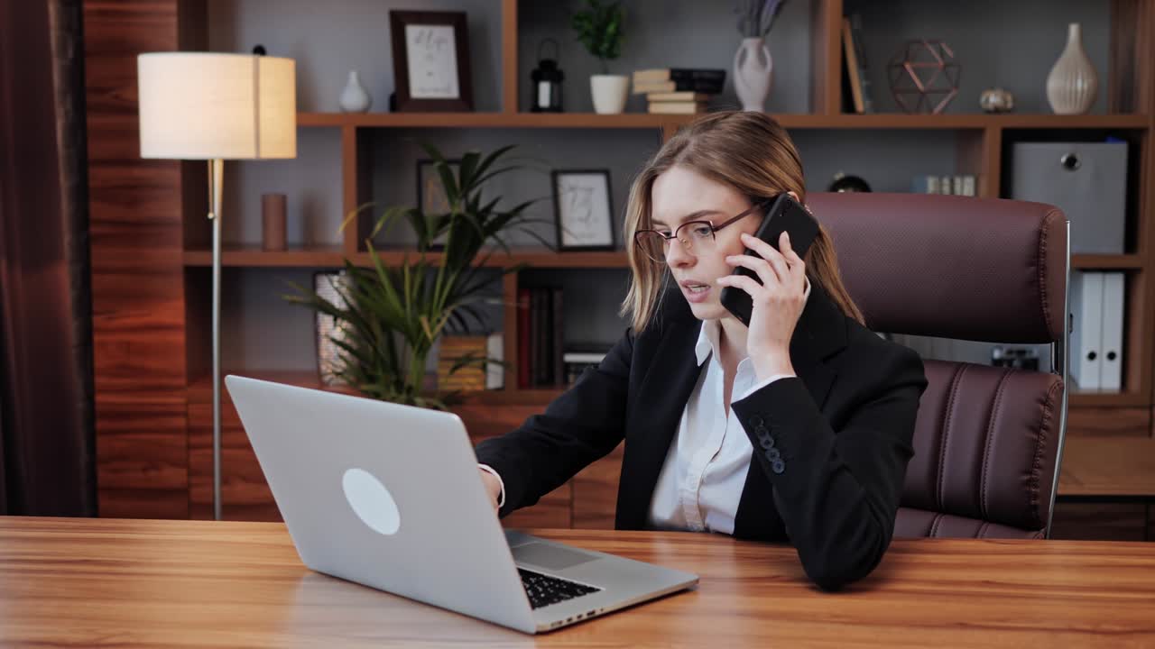 Donna d'affari professionista che usa il laptop durante una conversazione telefonica.