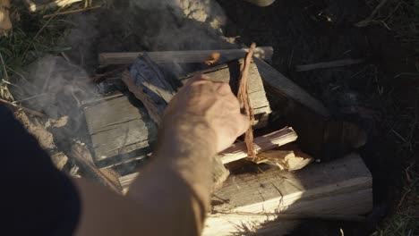 colocando kinderling en un fuego de campamento humeante humeante