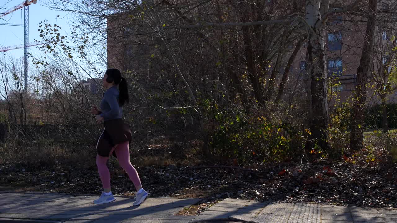 Woman jogging with headphones in city checking vital signs in smartwatch
