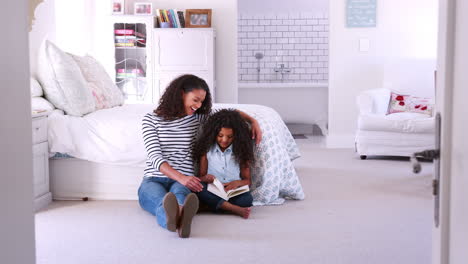 Una-Joven-Madre-De-Raza-Mixta-Leyendo-Un-Libro-Con-Su-Hija-En-Su-Habitación