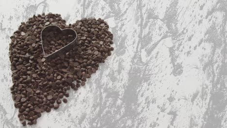 animation of chocolate crisps and heart shape mold over white and grey background