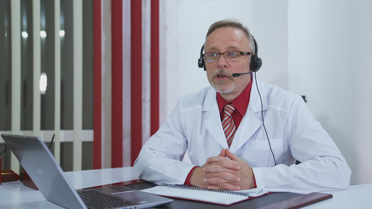 Conferenza online del medico in clinica. Bel medico maturo che consulta un paziente durante una videochiamata.
