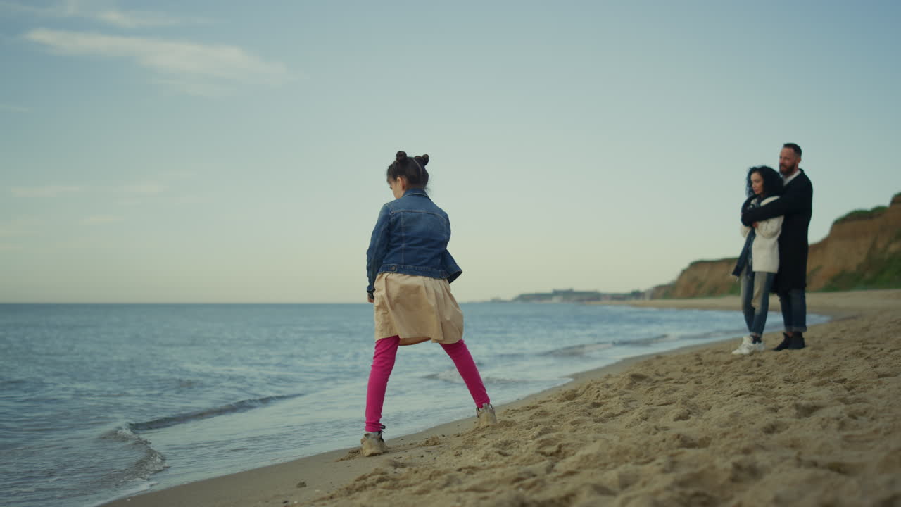 평화로운 가족이 바가 해변에서 함께 시간을 즐기고 있습니다. 소녀 아이가 부모를 놀고 있습니다.