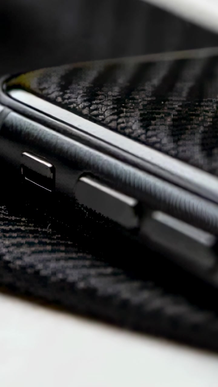 Vertikal video: Bevegelig kamera avslører smarttelefonens tre knapper på en svart matte, som viser metallkanten.