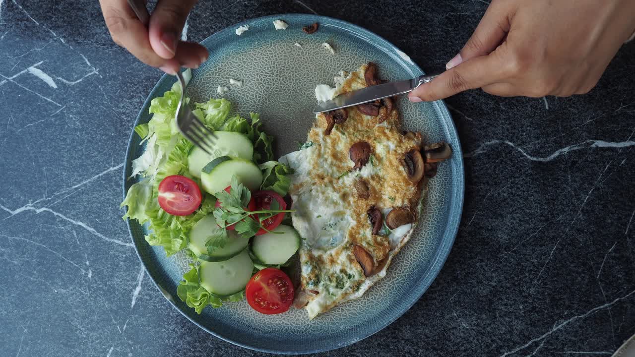 Woman eating a mushroom and vegetable omelette with salad