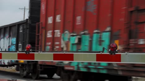 cargo train running on level crossing with low barriers and red lights in fort worth texas, usa