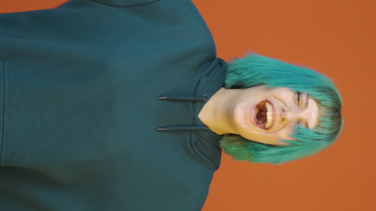 video vertical de una mujer joven haciendo señas de rocker y bailando.