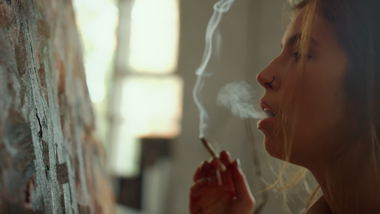 mujer joven fumando en el interior. pintor creativo buscando una imagen en el lugar de trabajo.