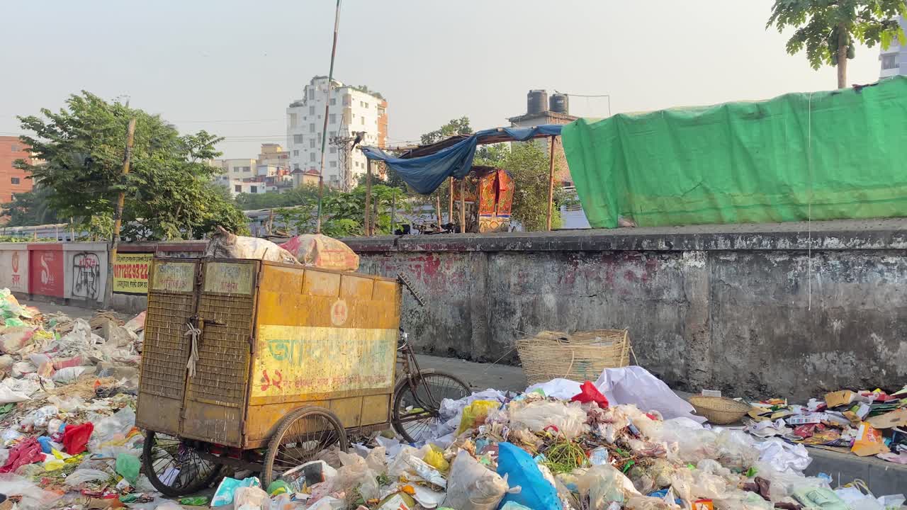 carro de basura junto a la basura junto a la pared con el tren pasando en dhaka, bangladesh