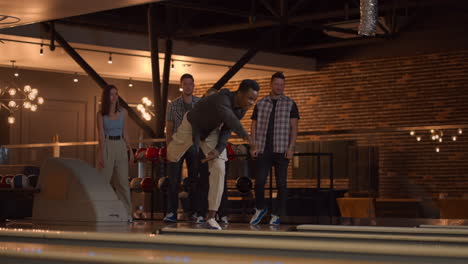 general plan black male bowling player throws ball with support from friends and rejoices by knocking out a strip