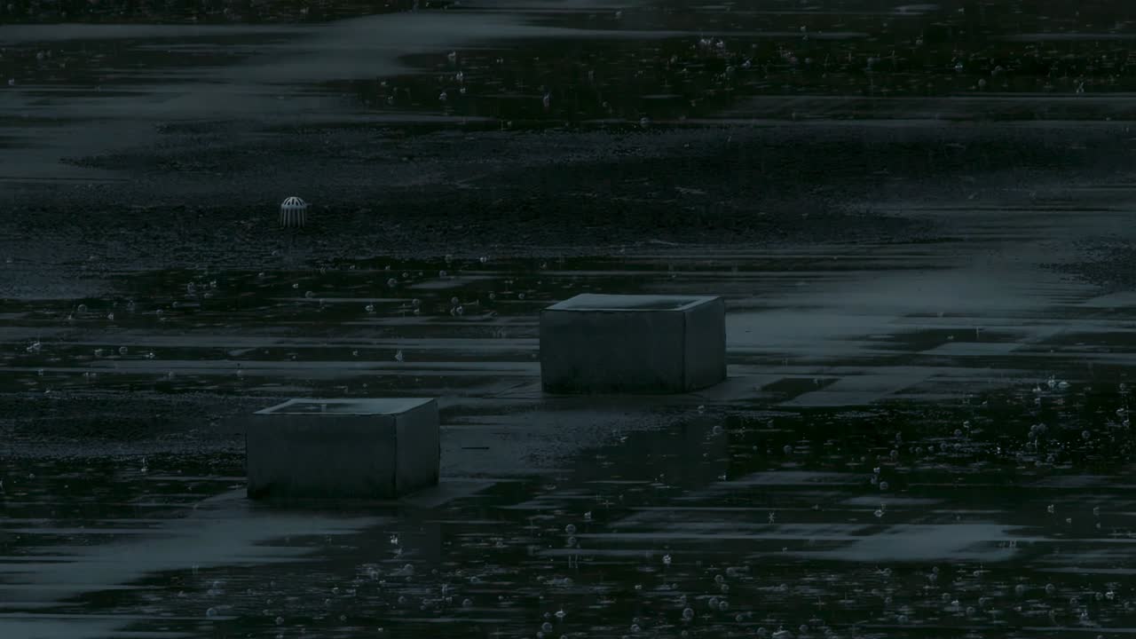 Establishing shot. Rain falling on apartment building roof in slow motion.