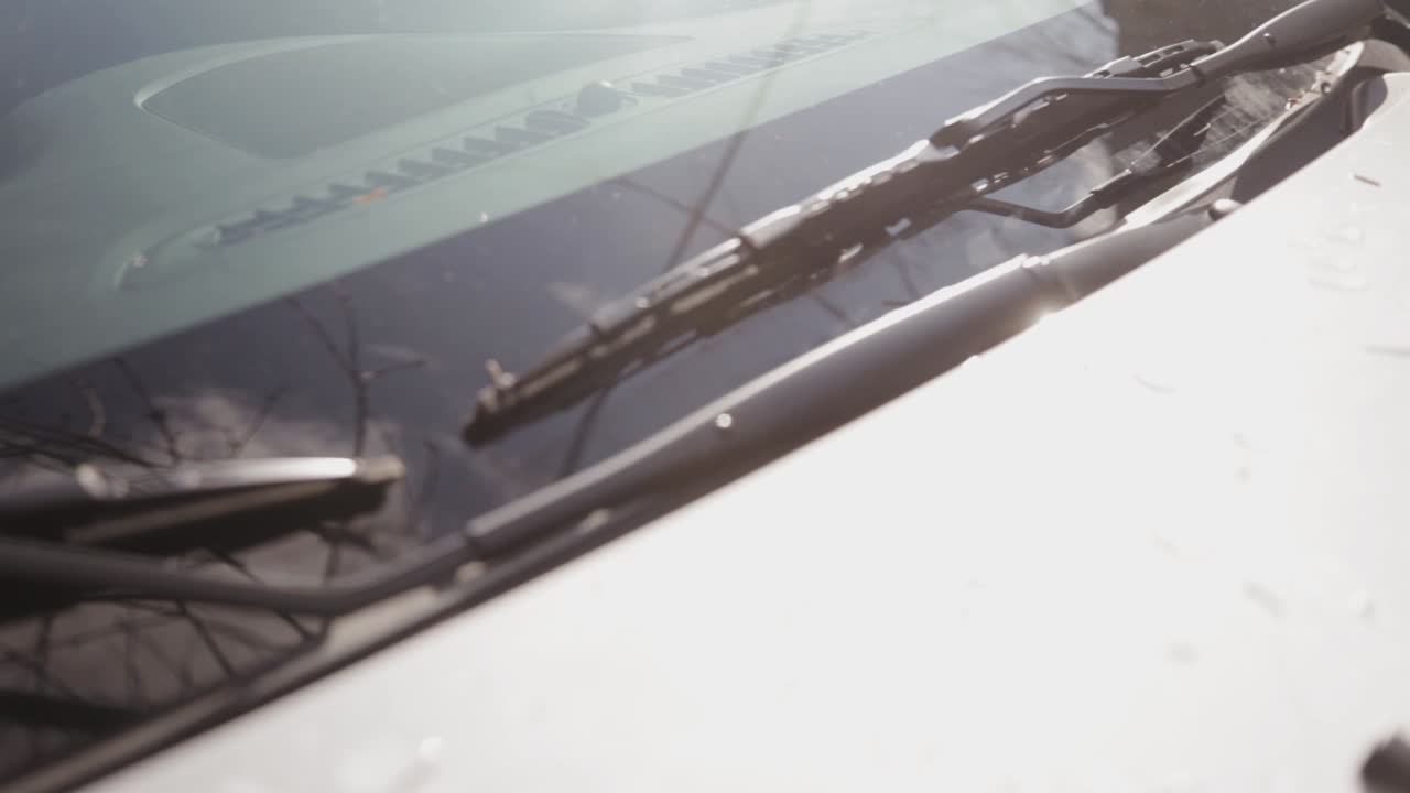 A White Vehicle Under The Heat Of The Sun, Checking If The Windshield And Wipers Are Clean - Close Up Shot