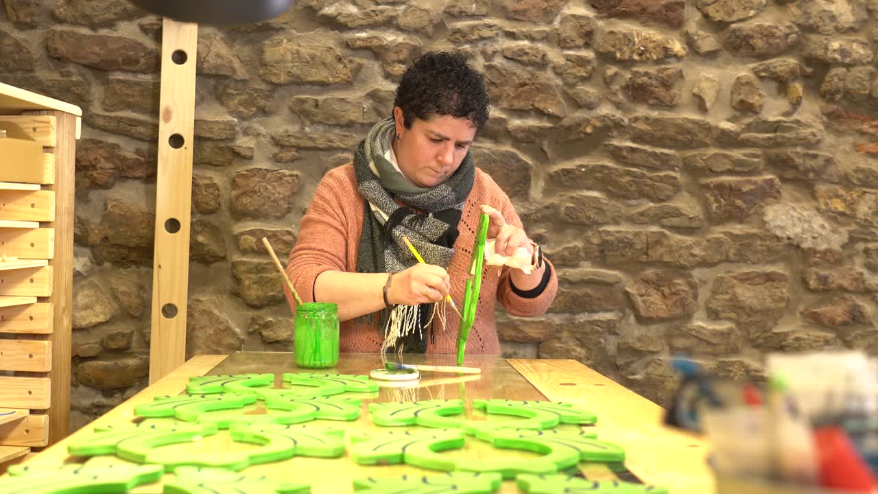 Woman painting wooden crafts green