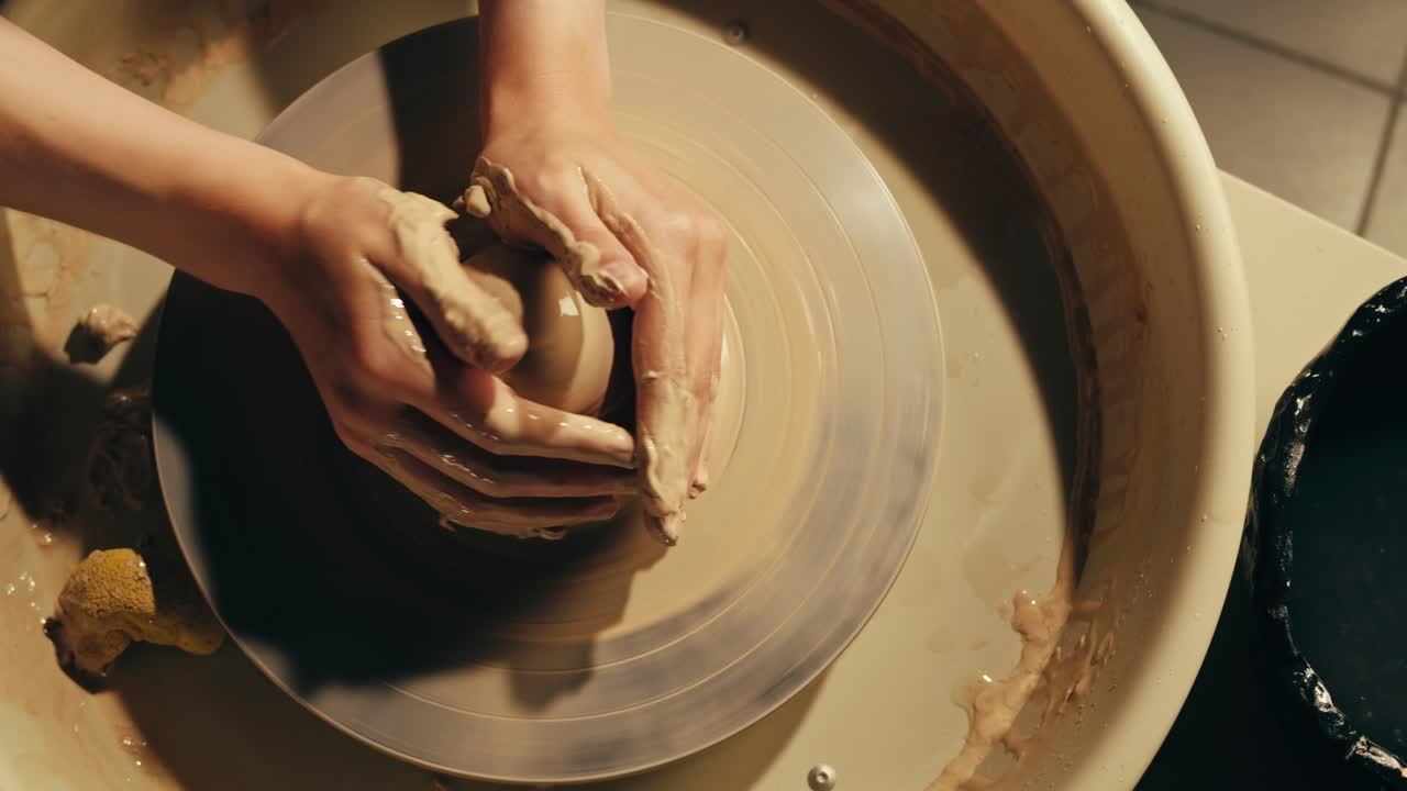 mujer moldeando arcilla en una rueda de cerámica