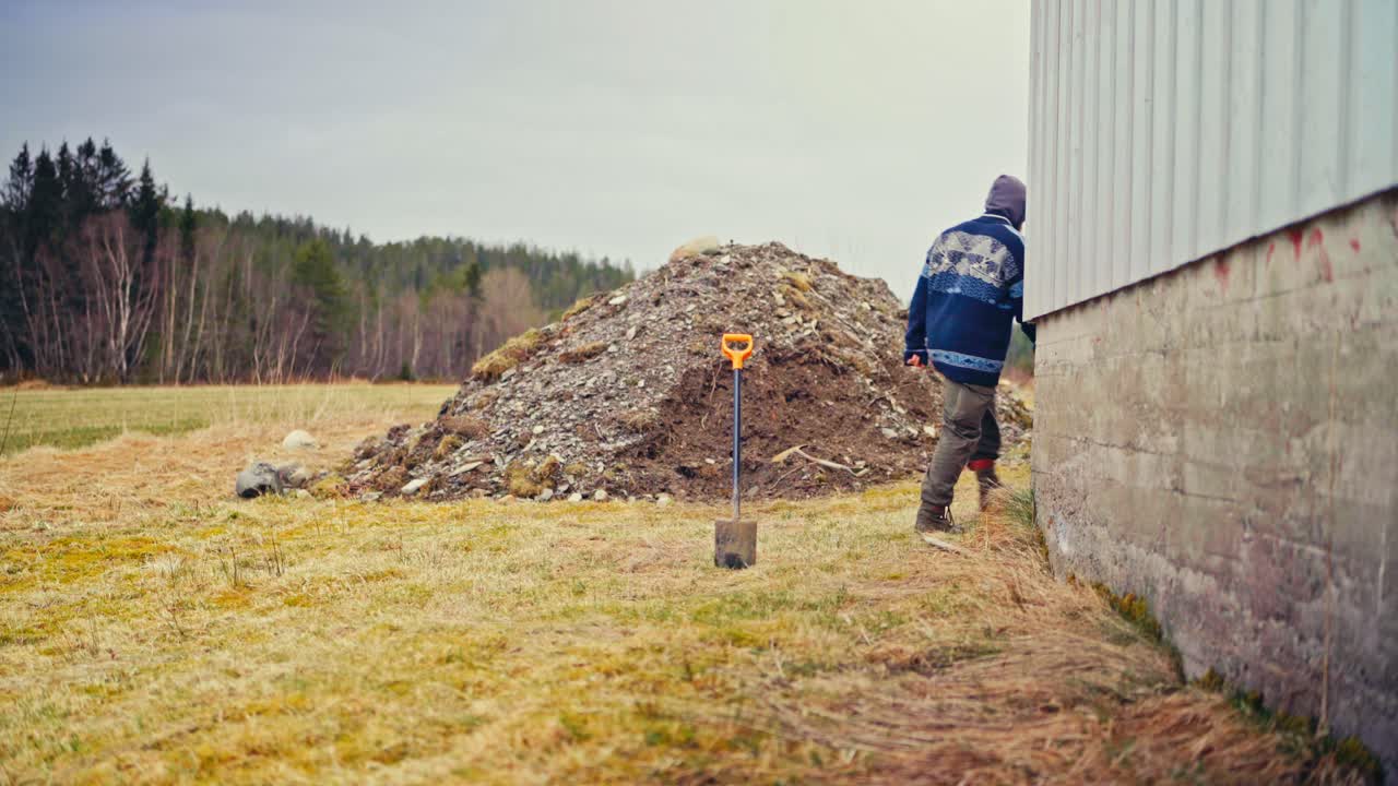 A Man is Transporting Poles in a Wheelbarrow to be Charred for Preservation - Static Shot