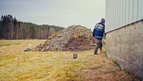 a man is transporting poles in a wheelbarrow to be charred for preservation - static shot