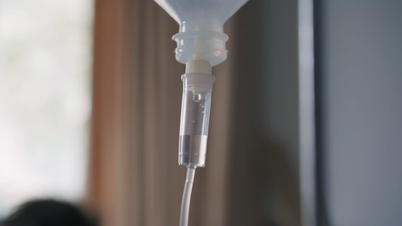 Focus on an intravenous drip system conveying medical fluids in a healthcare environment.